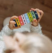 Child holding a colorful number block against a wooden background