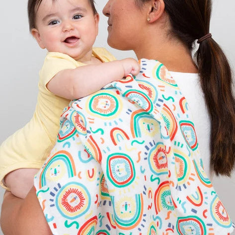 Woman holding a baby with a colorful patterned wrap on a plain background