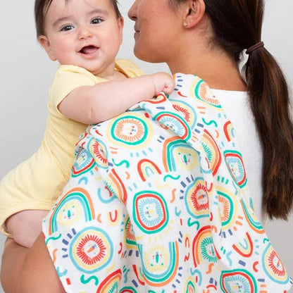 Woman holding a baby with a colorful patterned wrap on a plain background