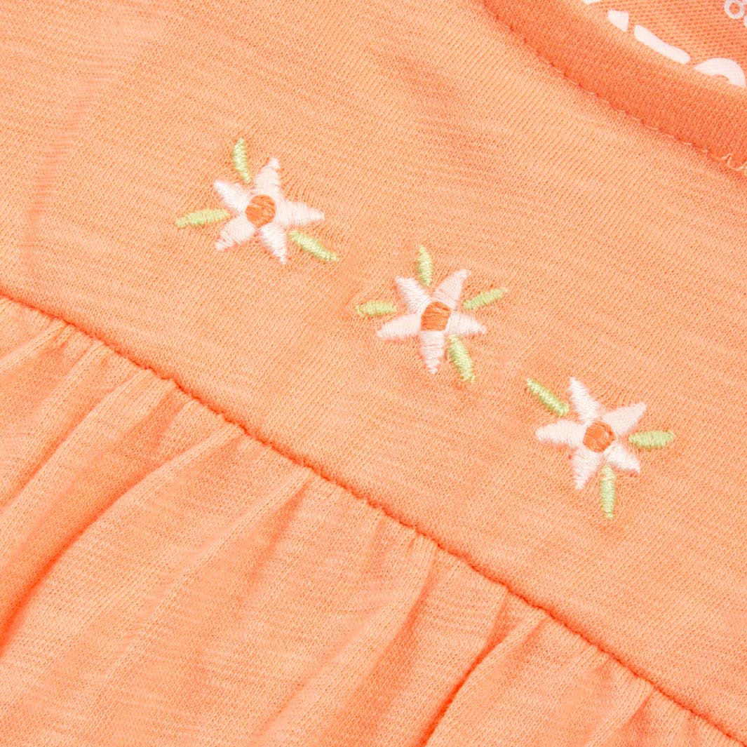 Close-up of an orange fabric with floral embroidery