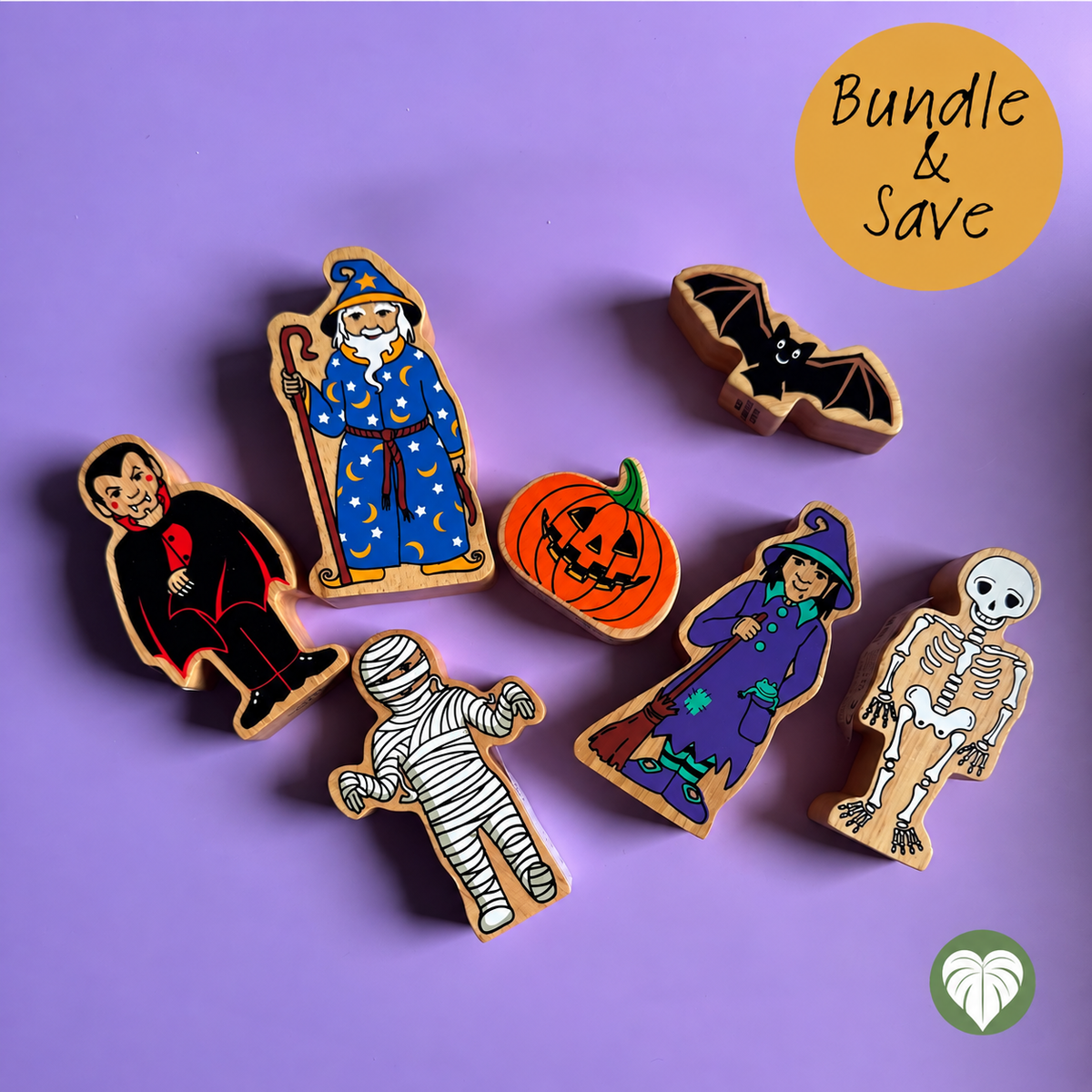 A set of six hand-painted wooden Halloween-themed toys arranged on a solid purple background. The set includes a vampire, a wizard, a bat, a jack-o'-lantern, a witch, and a skeleton.