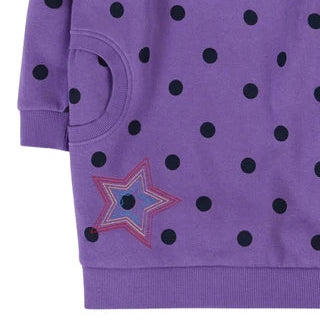 A close-up of a purple long-sleeve sweatshirt with black polka dots and a star patch on the front pocket.