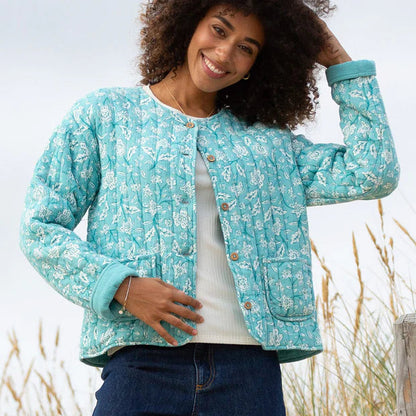 Woman wearing a turquoise floral jacket in a natural setting
