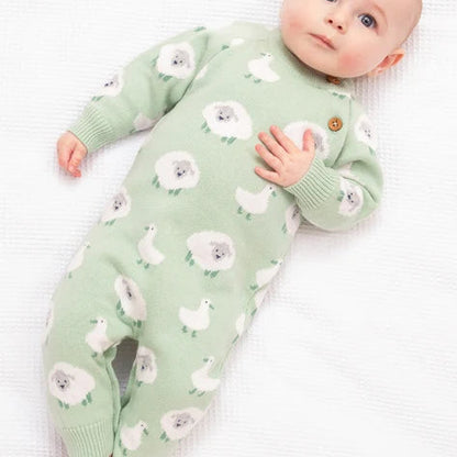 Baby wearing a green onesie with white floral patterns on a white background
