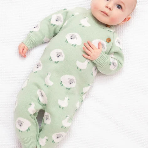 Baby wearing a green onesie with white floral patterns on a white background