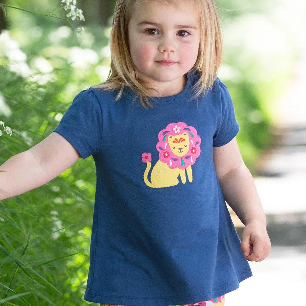 Child wearing a blue t-shirt with a lion graphic outdoors