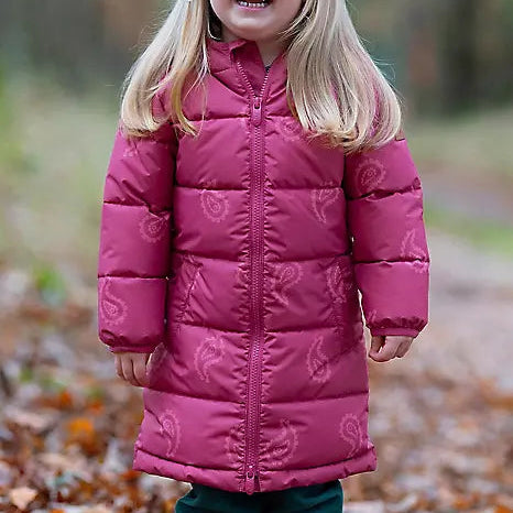 A young girl with blonde hair smiling outdoors in a long magenta quilted puffer coat with a subtle paisley pattern, paired with dark green pants.
