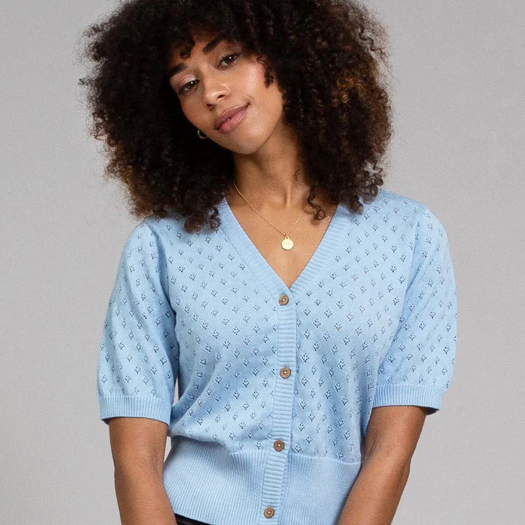 Woman wearing a light blue cardigan with a gray background