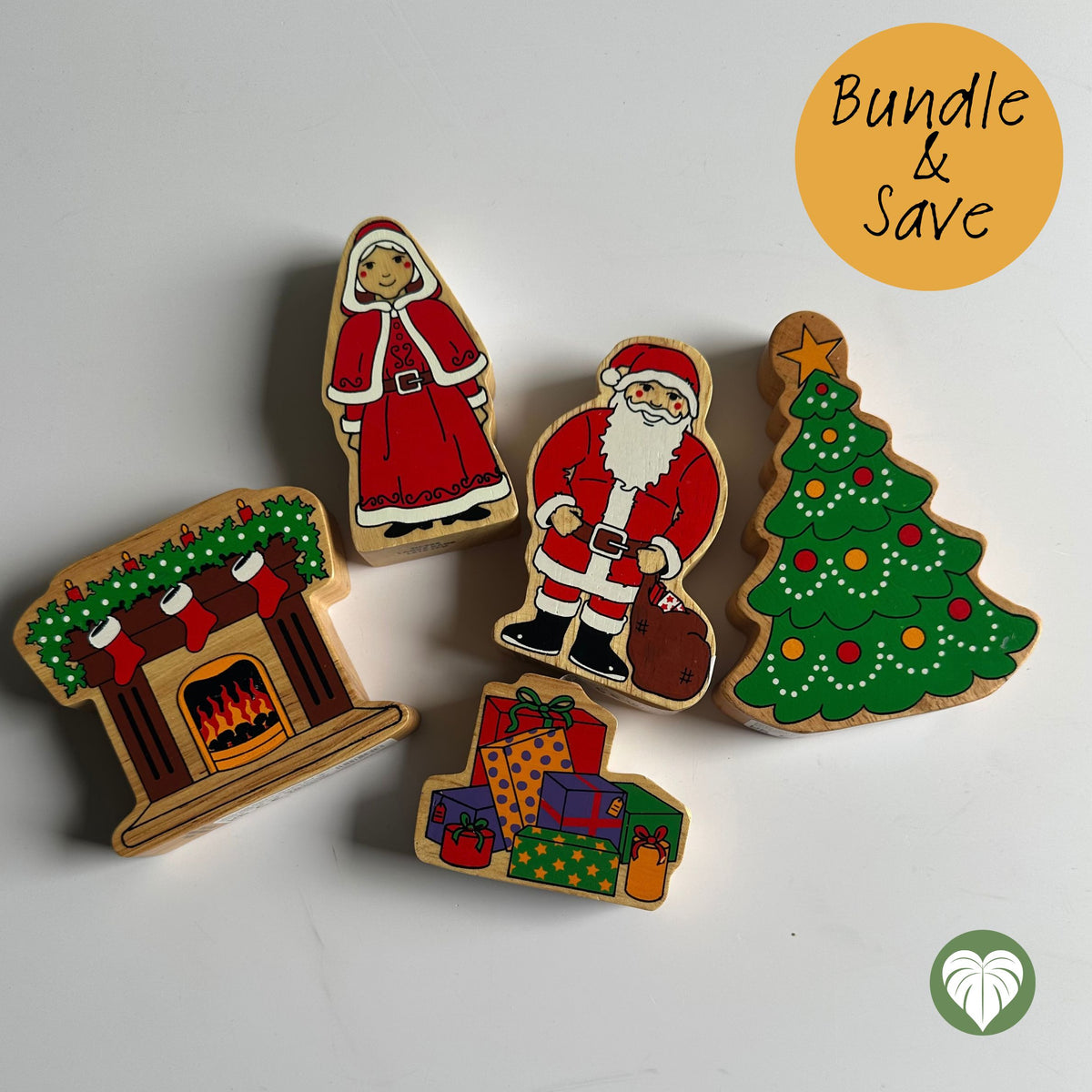 Five hand-painted wooden Christmas-themed cutouts arranged on a white surface: a fireplace with stockings and a fire, Santa Claus, a Christmas tree, a stack of presents, and a woman in a red dress. A yellow circle in the top right says 'Bundle & Save'.