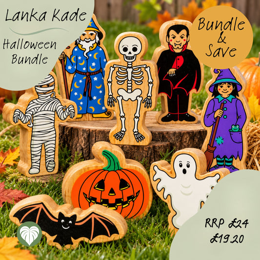 A set of hand-painted wooden Lankan Kade Halloween figures displayed on a rustic tree stump with autumn leaves and grass. The figures include a mummy, skeleton, vampire, witch, ghost, bat, and jack-o'-lantern.
