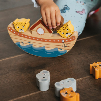 Child playing with wooden animal toys on a wooden surface